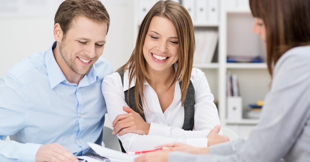 A young couple in a meeting with a professional woman looking at a document