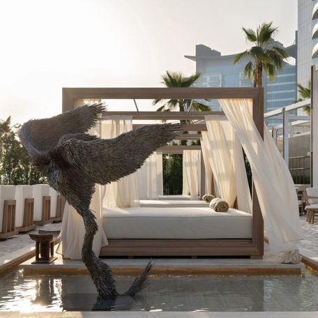 Side view of a SAN Beach cabana with a statue in a water feature in the foreground