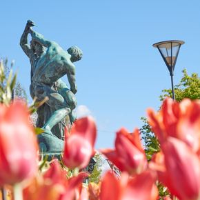 A green statue in Sweden with tulips in the foreground