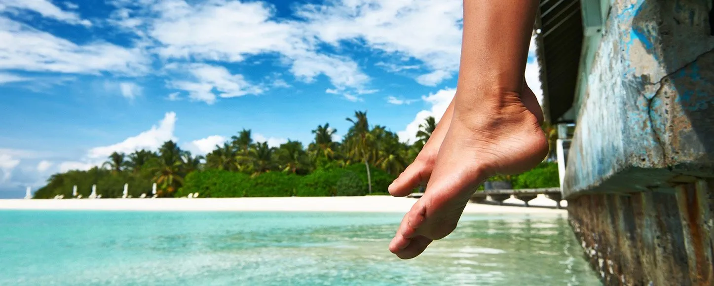 Persons feet hanging over the water near an island